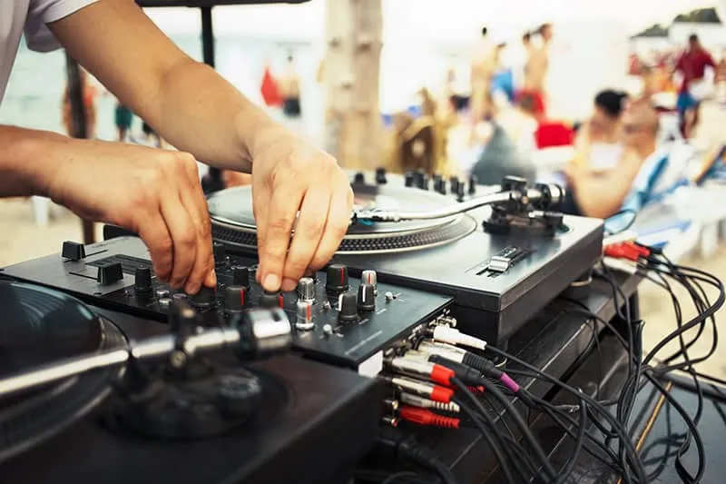 A DJ playing at a party with a focus on cables.