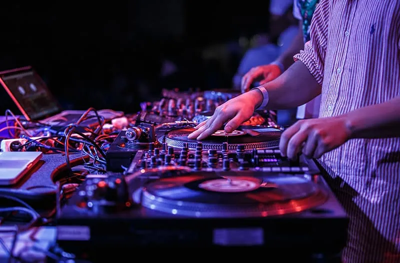 DJ scratching on DVS vinyl with a mixer and a laptop in the background.