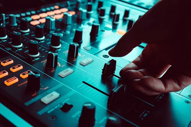 Close up photo of a DJ using channel faders on a DJ mixer.