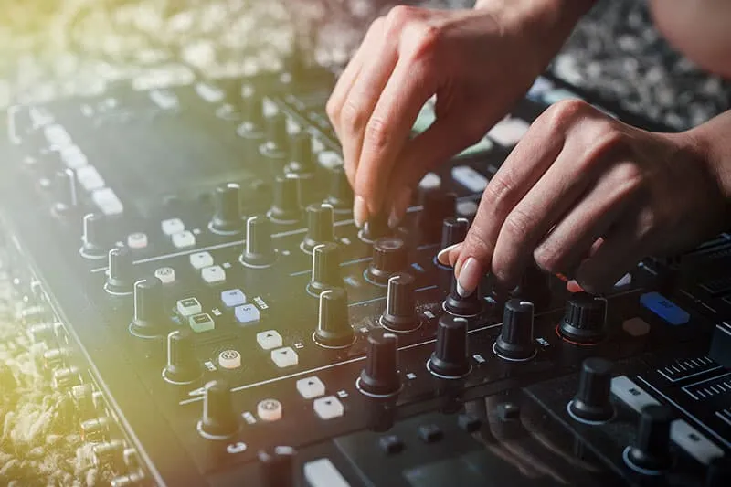 DJ altering the EQ on a DJ mixer.