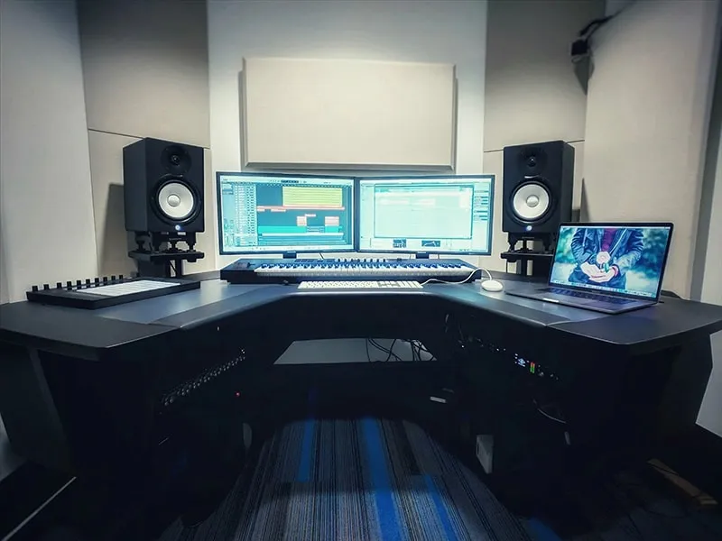 Music studio with studio monitors, keyboard, dual monitors and a laptop.