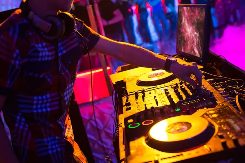 DJ mixing with his headphones around his neck.
