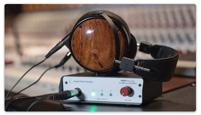 A pair of audiophile headphones sitting on top of a headphone amplifier.