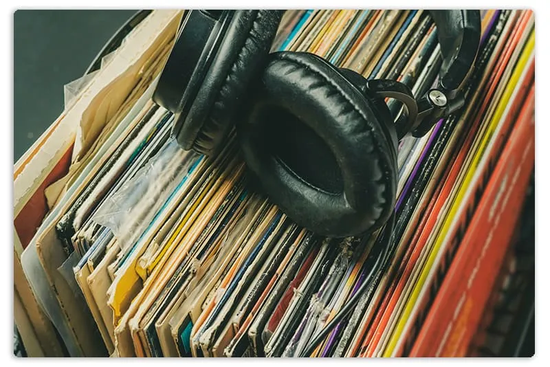 Headphones sitting on top of a pile of records.