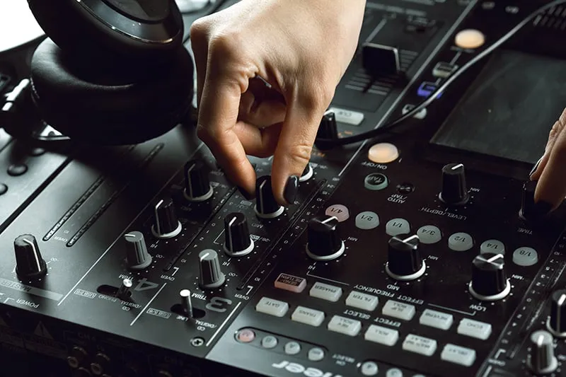 DJ adjusting EQ on a DJ mixer.