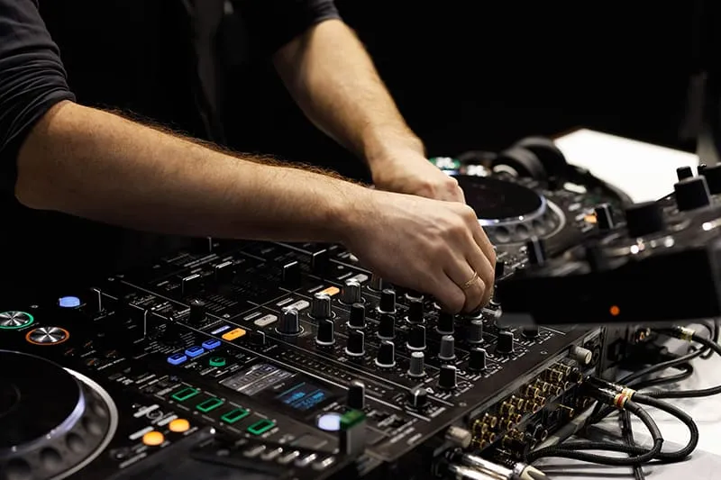 DJ adjusting EQ on a DJ Mixer