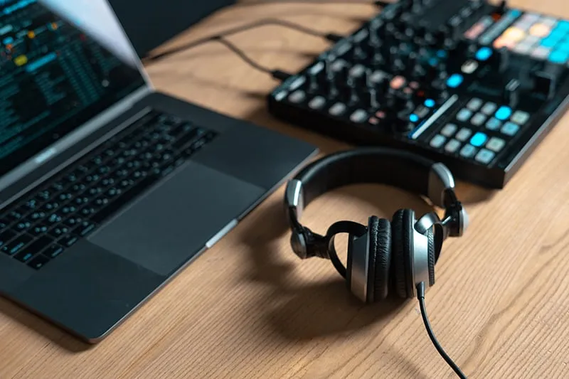 DJ Controller, Laptop and Headphones on a desk.