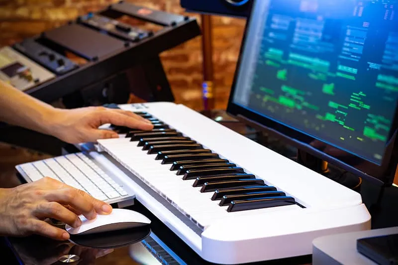 Home music studio with a keyboard in front of a monitor.