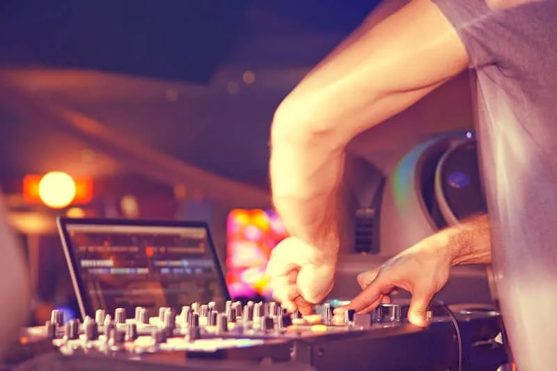 DJ mixing tracks with a laptop in the background