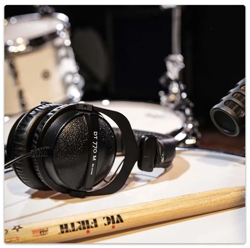 A pair of over-ear headphones sitting on top of a drum kit.