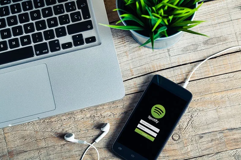 Photo of a laptop and phone with Spotify on the screen