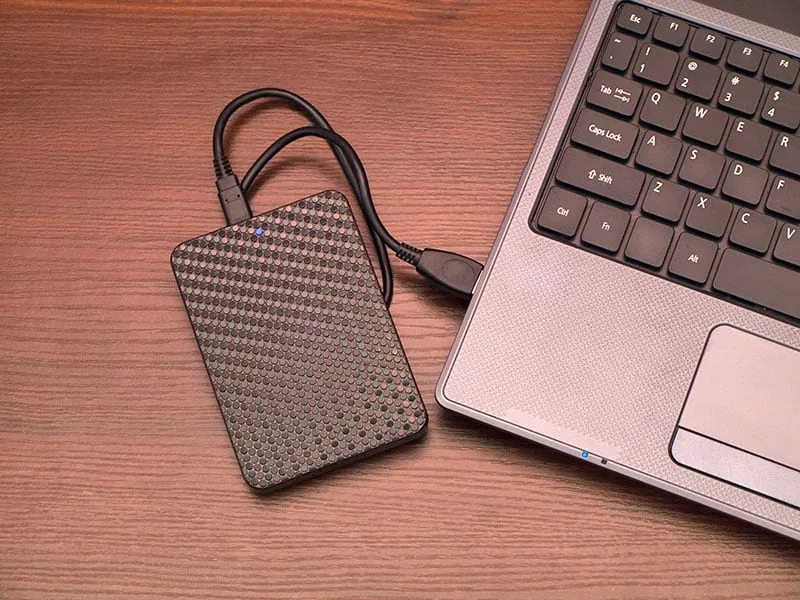 Photo of a laptop with a portable hard drive plugged in.