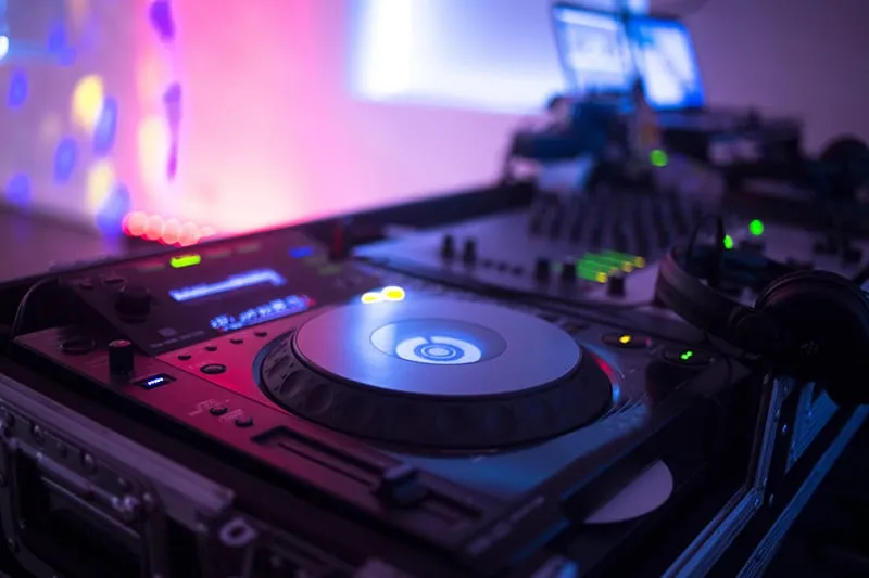 DJ gear set up at a function with colorful lighting.