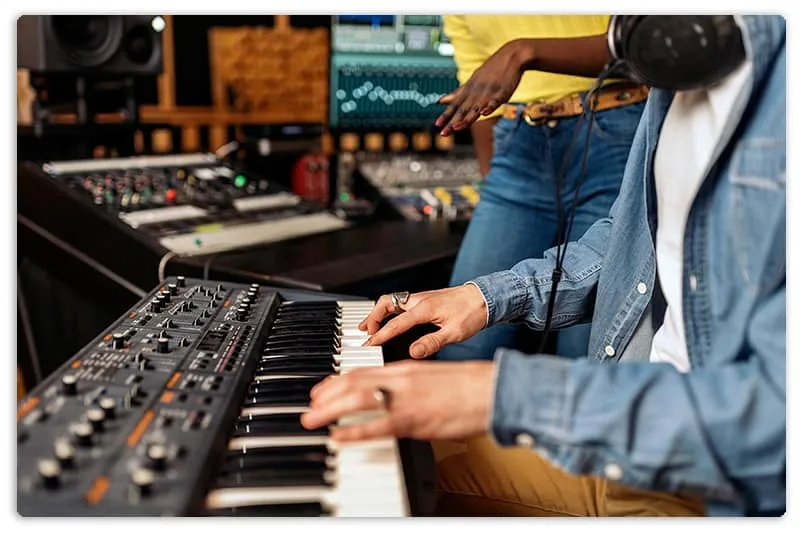 Photo of a person using a keyboard in a music studio.