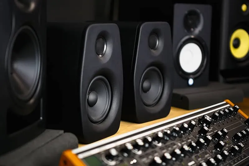 A selection of studio monitors sitting on a mixing console.