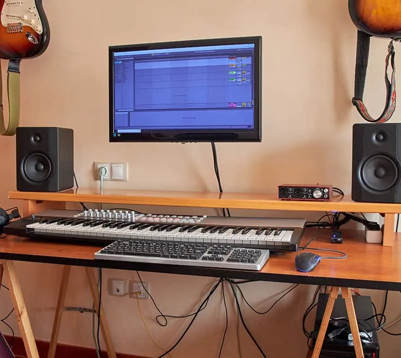 Home music studio with a keyboard and guitars hanging on the wall.