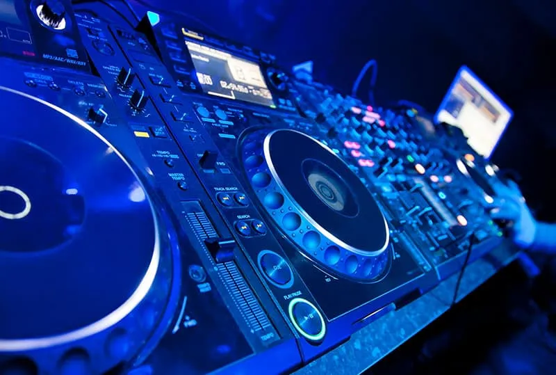 Pro DJ gear with laptop in the background.