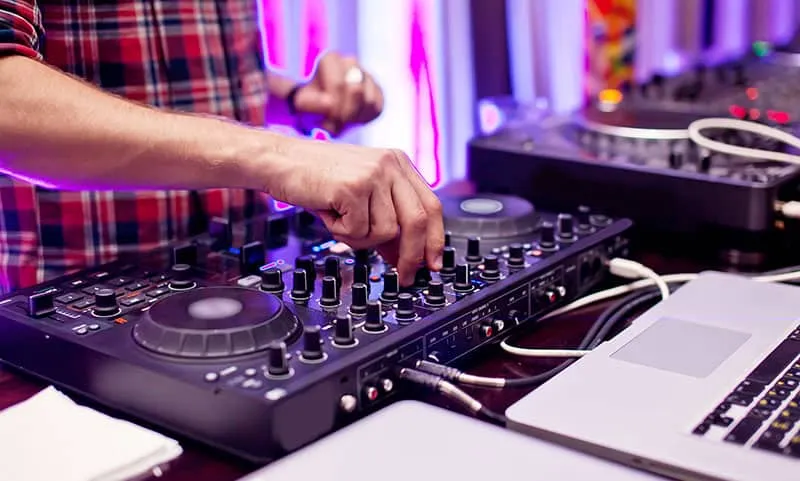Photo of a DJ playing on a DJ controller.
