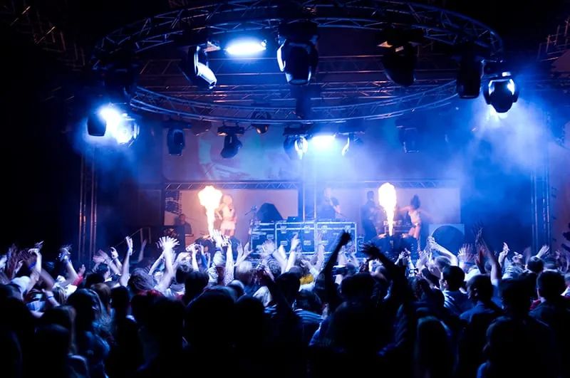 People at a concert with a DJ on stage